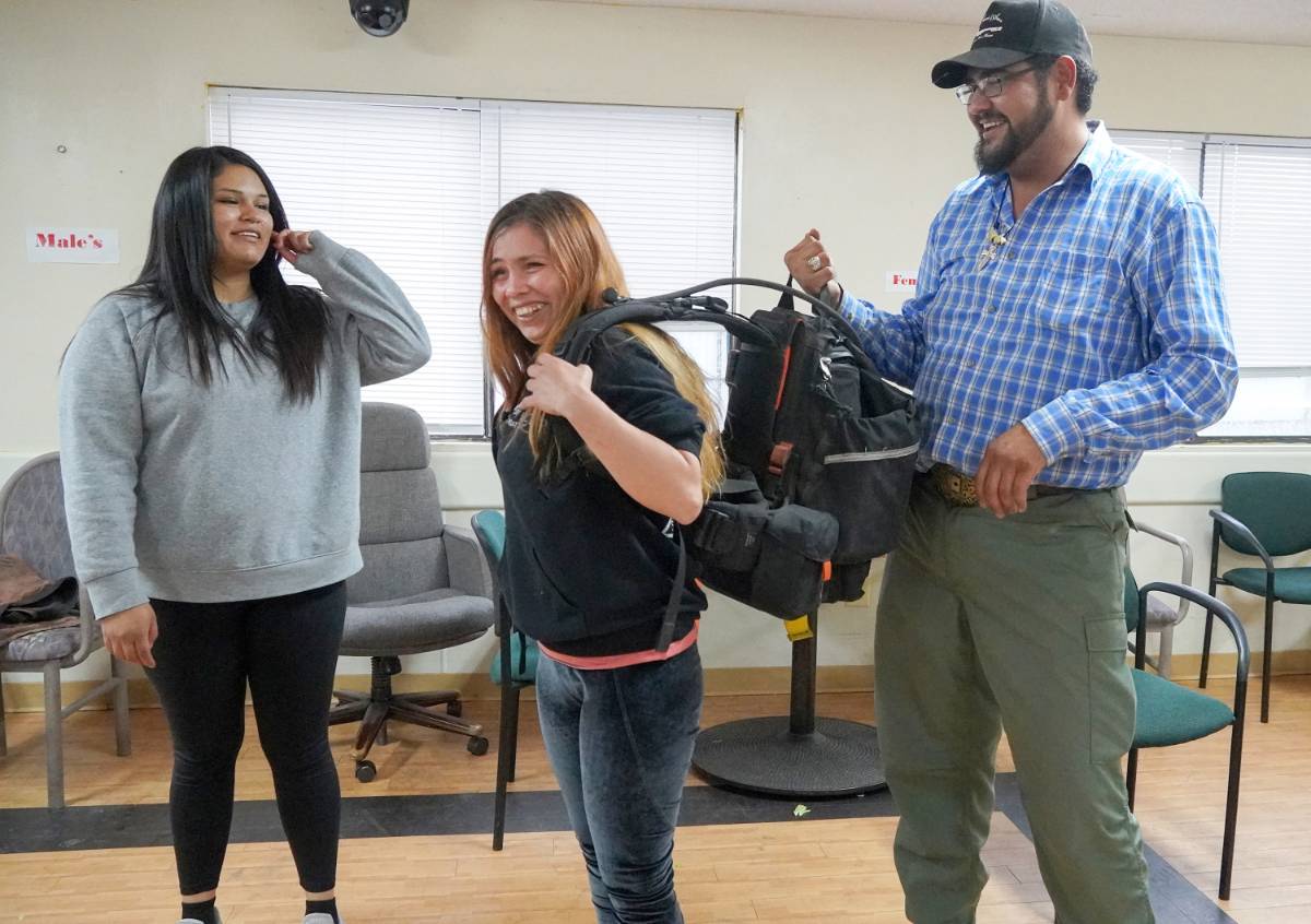 Firefighter Adam Gurule(Chama State Forestry District), helps one of the Wildland Firefighting course participants gets a feel for the backpack she will carry in the field. 